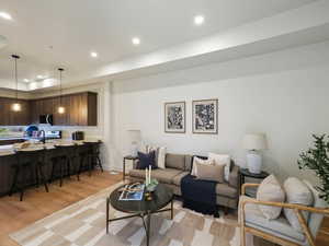 Living room featuring recessed lighting, light wood-style flooring, and a tray ceiling