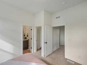 bedroom featuring light colored carpet and ensuite bathroom