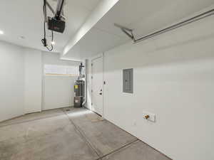 Garage with electric panel, secured water heater, and a garage door opener