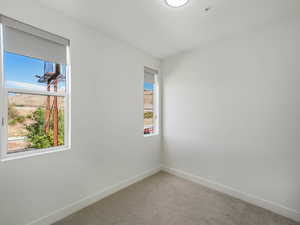 Carpeted spare room featuring baseboards