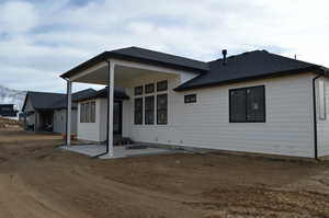 Back of property with a patio and roof with shingles