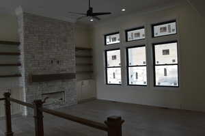 Unfurnished living room featuring crown molding, a stone fireplace, a ceiling fan, dark wood finished floors, and recessed lighting