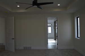 Spare room featuring a tray ceiling, carpet, a ceiling fan, and recessed lighting
