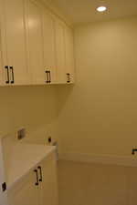Laundry area featuring recessed lighting, cabinet space, hookup for a washing machine, electric dryer hookup, and light tile patterned flooring
