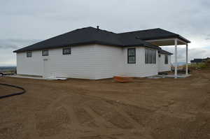 View of side of home featuring a patio and roof with shingles
