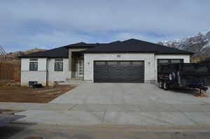 View of front of property with stone siding, an attached garage, driveway, and a shingled roof