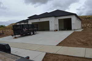 View of front facade featuring concrete driveway, a garage, and a shingled roof