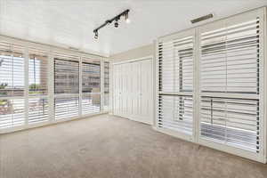 Southwest corner bedroom with closet outfitted with drawers.  Sliding door to South Balcony with window view of west balcony off the primary bedroom.