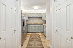 Kitchen with green cabinets, backsplash, stainless steel appliances, and a large storage areas