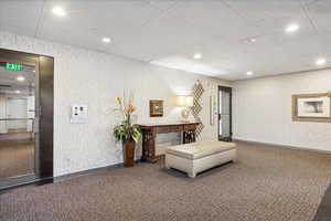 Common area featuring a drop ceiling, recessed lighting, and wallpapered walls