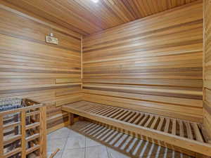 Sauna / steam room featuring wooden walls, tile patterned floors, and wooden ceiling