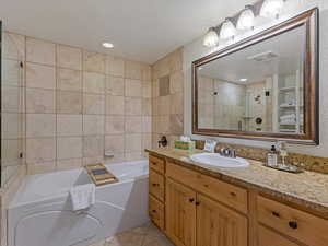Bathroom featuring vanity, a garden tub, a stall shower, light tile patterned floors, and tile walls