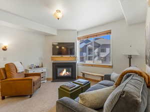 Carpeted living room featuring a fireplace with flush hearth and a textured wall