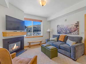 Carpeted living area featuring a glass covered fireplace and baseboards