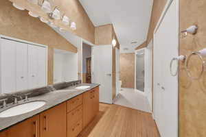 Bathroom with double vanity, a stall shower, and light wood finished floors