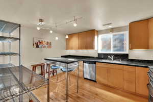 Kitchen featuring light wood-style floors, decorative light fixtures, stainless steel appliances, and track lighting