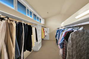Spacious closet with light carpet and lofted ceiling