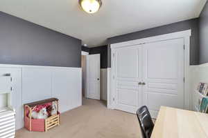 Office with wainscoting, a decorative wall, and light carpet