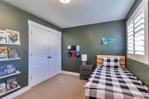 Bedroom with light carpet and a closet