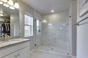 Full bathroom with a walk in closet, a marble finish shower, vanity, light tile patterned flooring, and recessed lighting