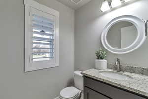 Half bathroom featuring vanity and toilet