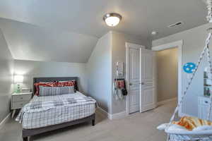 Bedroom with light colored carpet and vaulted ceiling