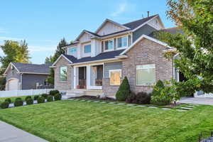 Craftsman house with covered porch, board and batten siding, a garage, and brick siding
