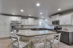 Kitchen with white cabinetry, decorative backsplash, appliances with stainless steel finishes, and recessed lighting