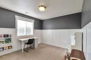 Office with wainscoting, light colored carpet, and a decorative wall