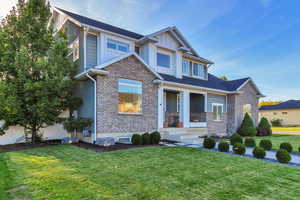 Craftsman inspired home featuring a front lawn, covered porch, brick siding, and board and batten siding