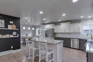 Kitchen featuring light stone counters, light wood-style floors, white cabinetry, and recessed lighting