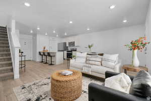 Living area with stairway, light wood-type flooring, recessed lighting, and a textured ceiling
