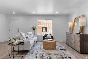 Living room with light wood finished floors, a textured ceiling, and recessed lighting