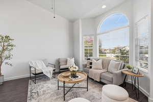 Living room with dark wood finished floors, a ceiling fan, and lofted ceiling
