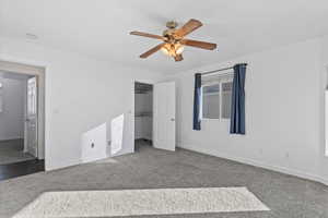 Unfurnished bedroom featuring carpet, a walk in closet, and ceiling fan