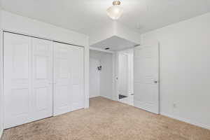 Bedroom featuring light carpet, a laundry closet, and a textured ceiling