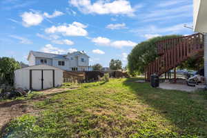 View of yard with a storage shed, a patio area, and stairway