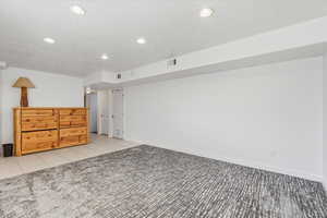 Family room featuring light colored carpet, light tile patterned flooring, recessed lighting, and a textured ceiling