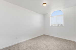 Carpeted bedroom with baseboards and vaulted ceiling