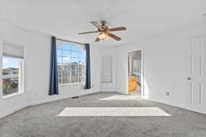 Unfurnished bedroom featuring light carpet, ceiling fan, and ensuite bathroom