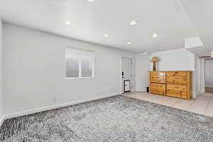 Family room with a textured ceiling, light tile patterned floors, light colored carpet, and recessed lighting