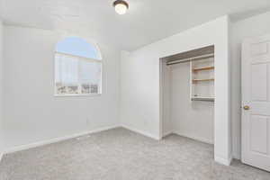 Bedroom featuring light colored carpet, a closet, and a textured ceiling