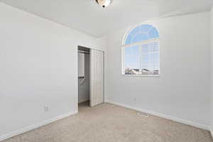 Bedroom with light colored carpet and a closet