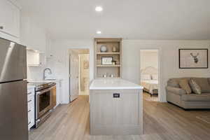 Kitchen with stainless steel appliances, white cabinets, tasteful backsplash, open shelves, and recessed lighting