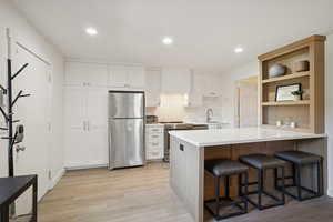 Kitchen with a kitchen bar, tasteful backsplash, a peninsula, stainless steel appliances, and white cabinetry