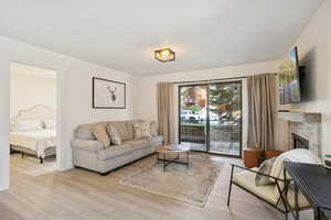 Living area with light wood-type flooring and a stone fireplace