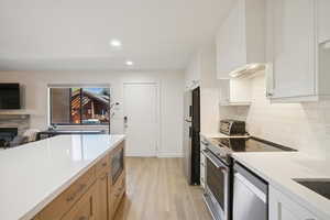 Kitchen with appliances with stainless steel finishes, recessed lighting, light wood-style floors, white cabinetry, and decorative backsplash