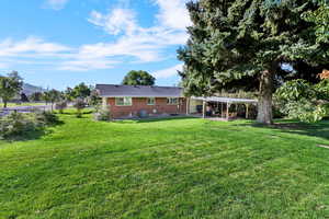 Rear view of house featuring a patio, a yard, brick siding, and a mountain view