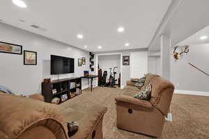 Carpeted living area with recessed lighting and baseboards
