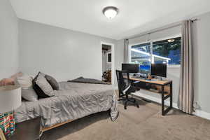 Bedroom featuring light colored carpet and a desk